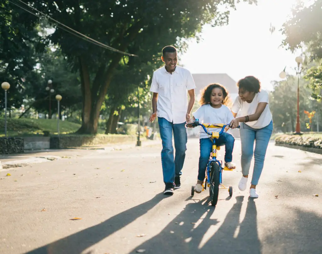 man-standing-beside-his-wife-teaching-their-child-how-to-ride-bicycle-