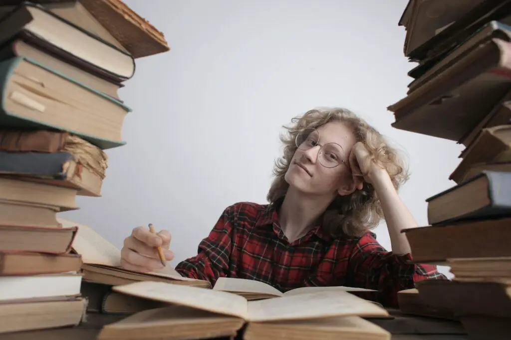 woman in red and black checked shirt smiling surrounded with books