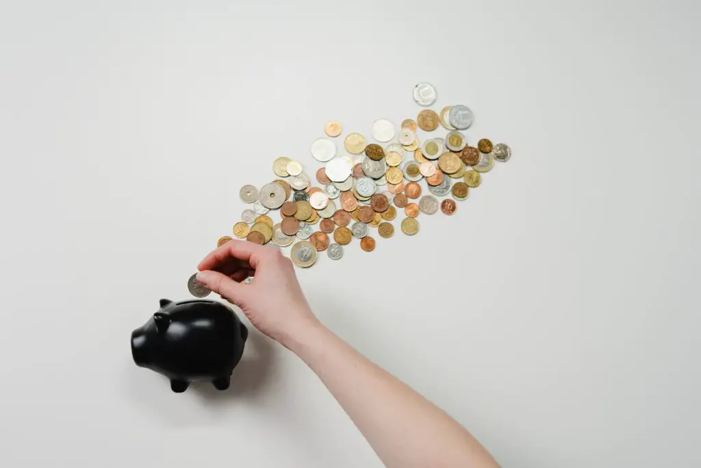 how to start investing in property with real money photo of a person putting coins on black piggy bank