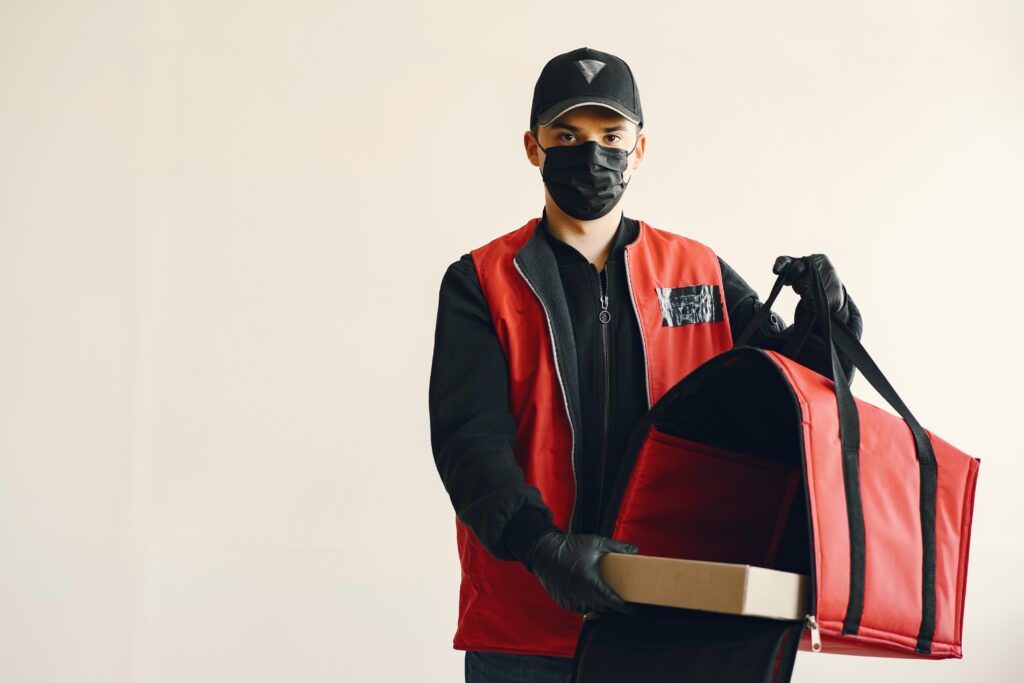 young-pizza-delivery-man-in-uniform-and-protective-mask