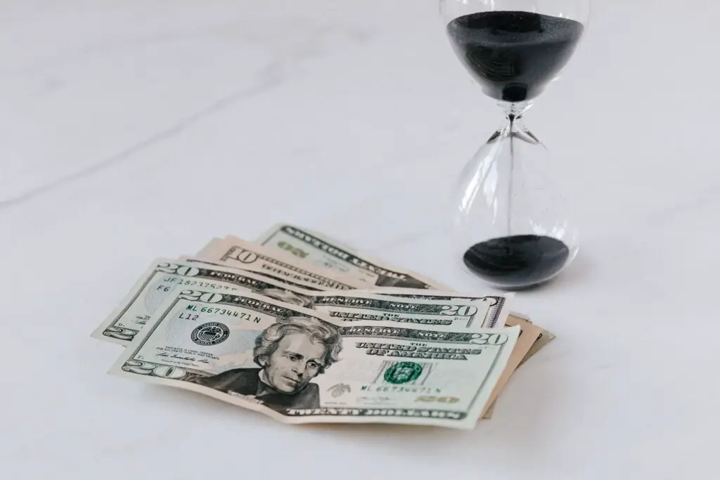 60000 a year is how much an hour- hourglass-near-heap-of-american-dollars-
