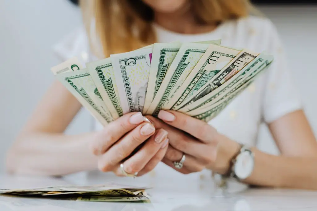woman-holding-fan-of-dollar-bills