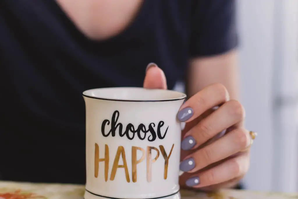 selective-focus-photography-of-person-touch-the-white-ceramic-mug-with-choose-happy-graphic