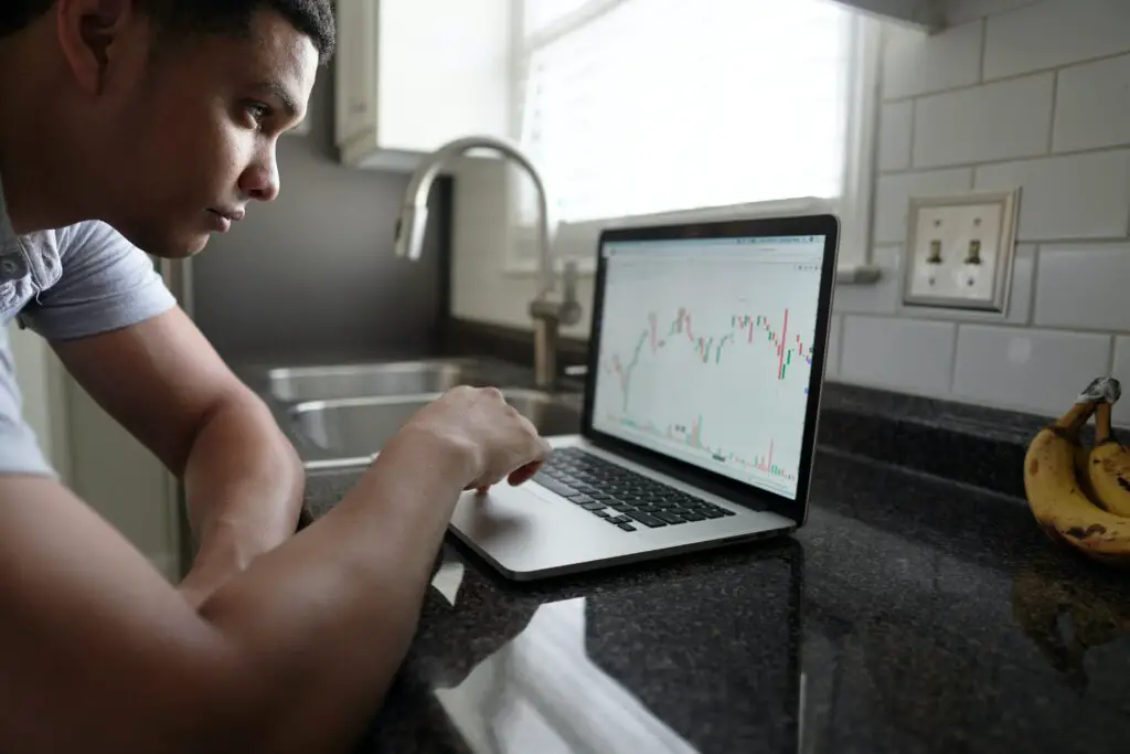 man examining candle stick chart on laptop