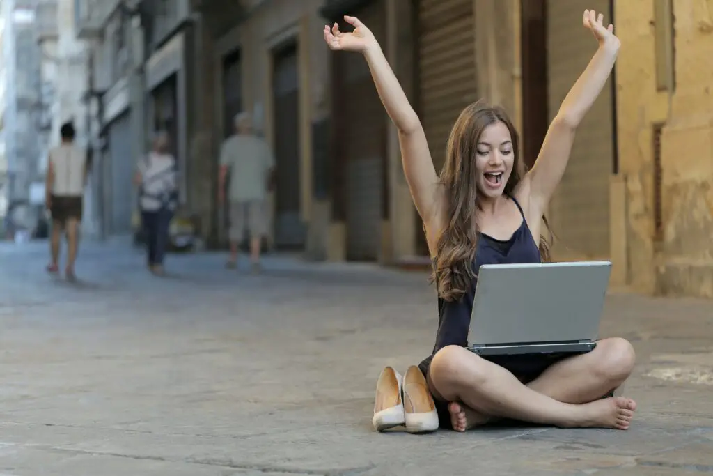 woman-raising-her-hands-up-while-sitting-on-floor-with-macbook-pro-on-lap
