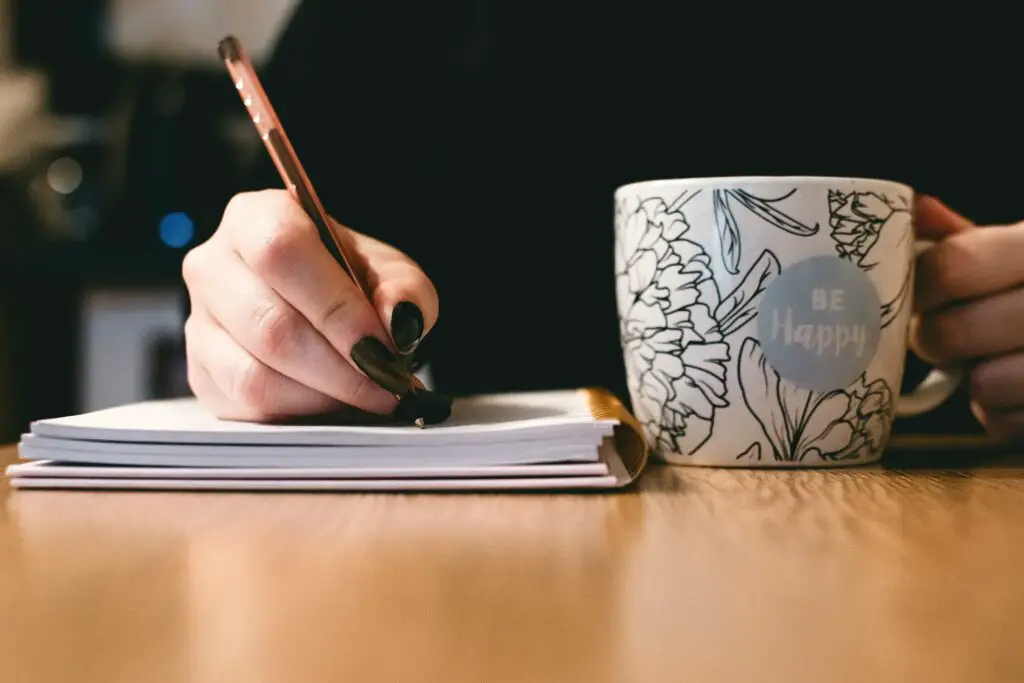 best side hustles for introverts- crop person writing and holding mug