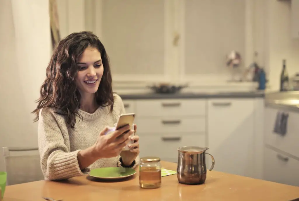 best side hustles for introverts young-woman-drinking-tea-and-using-smartphone