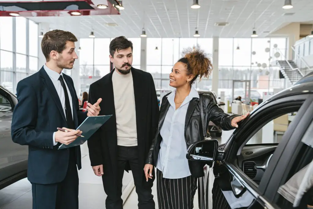 man-in-blue-business-suit-talking-to-woman-touching-the-car