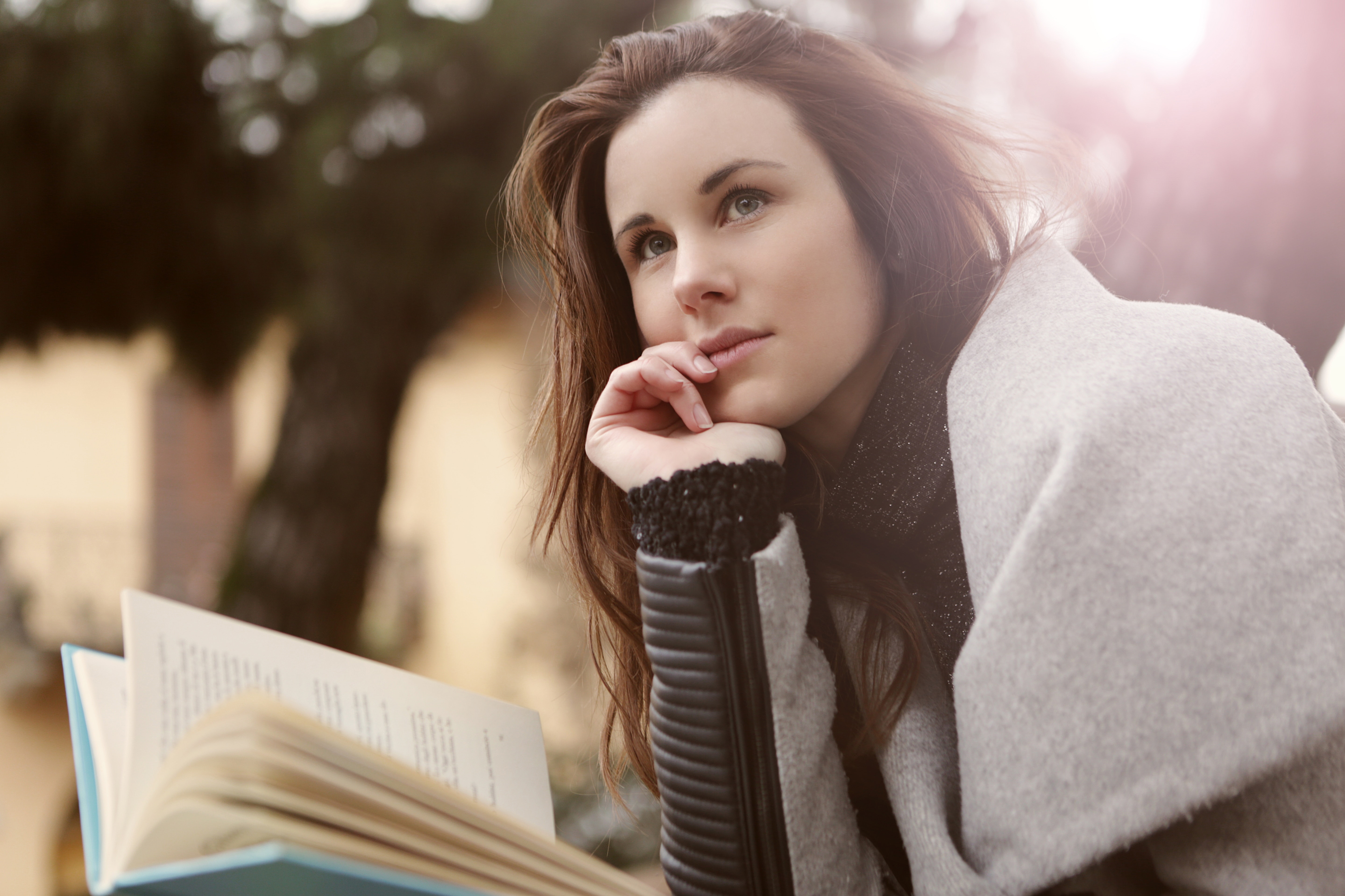 pensive woman in grey coat reading book
