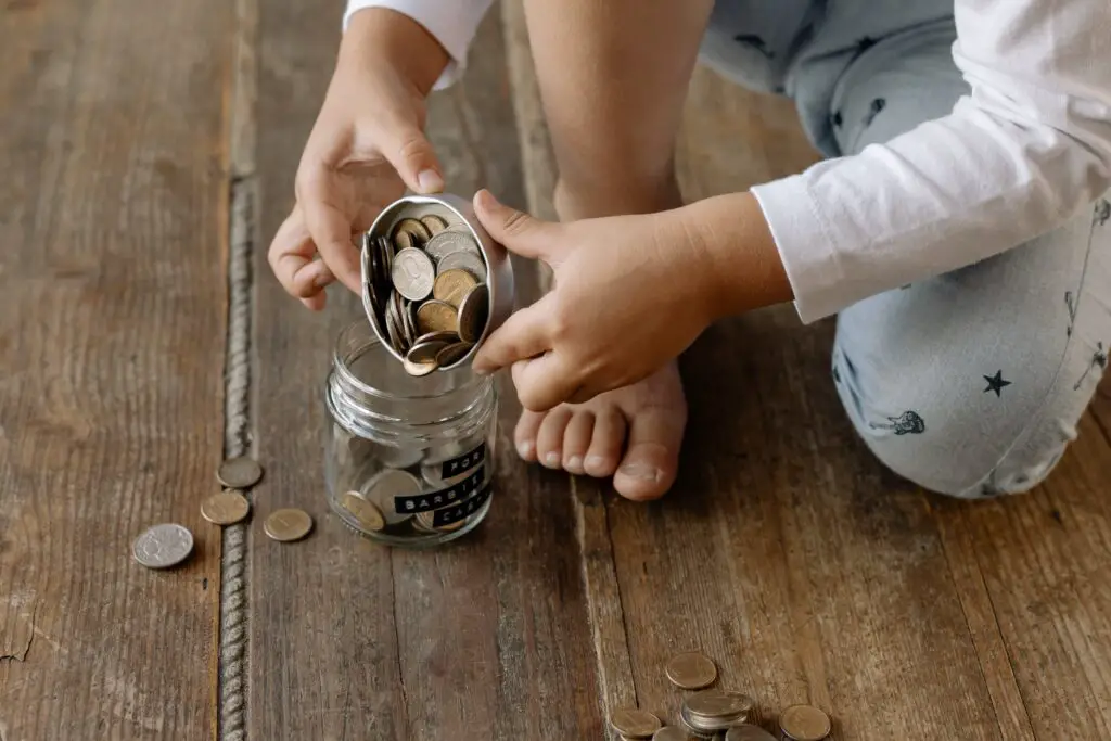 why can't I save money photo of crop child putting coins in jar