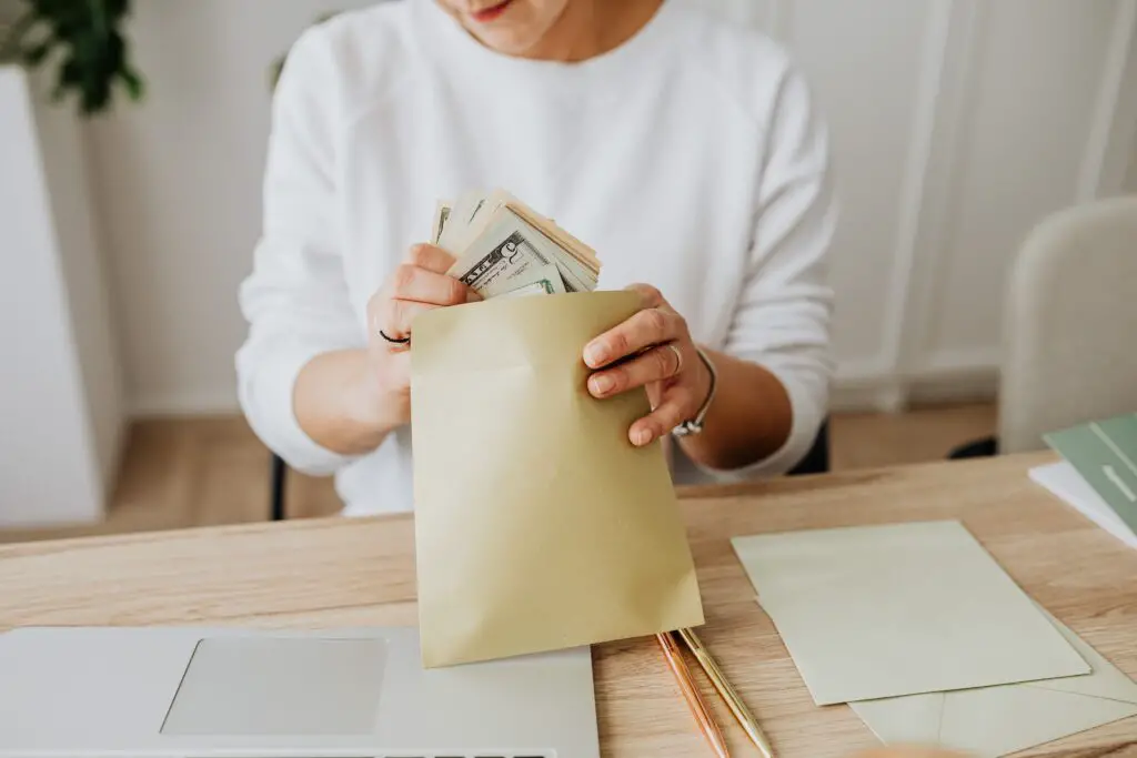 person wearing a sweater putting money inside an envelope